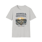 Light gray Comfort Colors unisex t-shirt with "Hooked & Obsessed" text and a fishing reel sunset graphic.