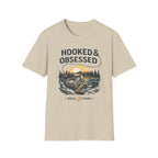 Beige Comfort Colors cotton t-shirt with "Hooked & Obsessed" text and a fishing reel graphic.