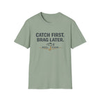 Comfort Colors sage green unisex t-shirt with "Catch First. Brag Later." text and fishing hook/fish graphic.