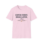 Light pink Comfort Colors unisex t-shirt with "CATCH FIRST. BRAG LATER." text and fishing hook graphic.