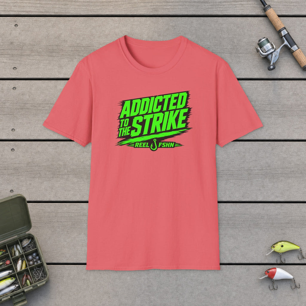Addicted To The Strike T-Shirt flat-laid on wooden dock boards beside a fishing rod and tackle box
