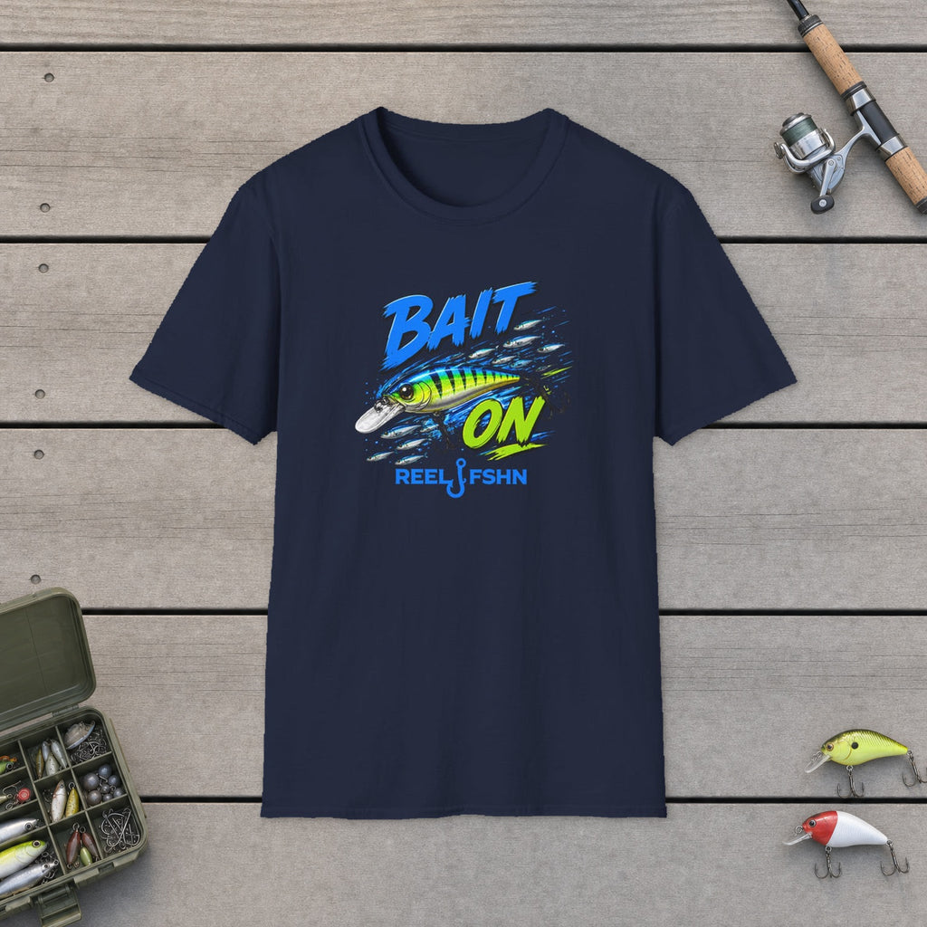 Bait On (single lure)  T-Shirt flat-laid on wooden dock boards beside a fishing rod and tackle box