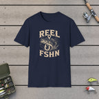 Bass Through Hook T-Shirt on a wooden dock with fishing rod, reel, tackle box and lures