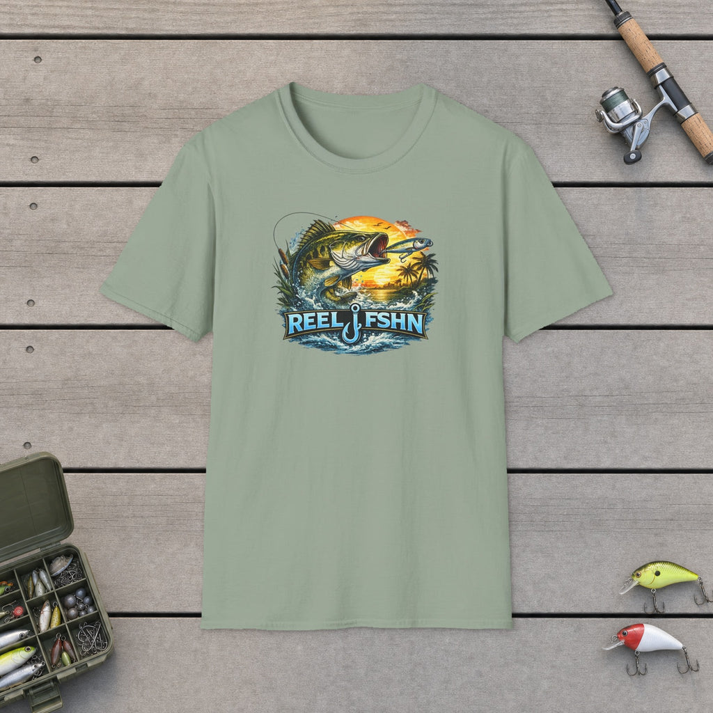 Bass with REEL FSHN Logo T-Shirt flat-laid on wooden dock boards beside a fishing rod and tackle box