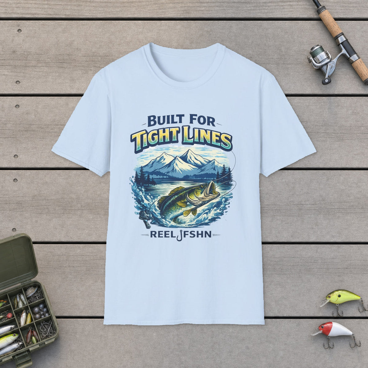 "Built for Tight Lines" T-Shirt on a wooden dock with fishing rod, reel, tackle box and lures