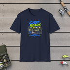 Cast Ready  T-Shirt on a wooden dock with fishing rod, reel, tackle box and lures