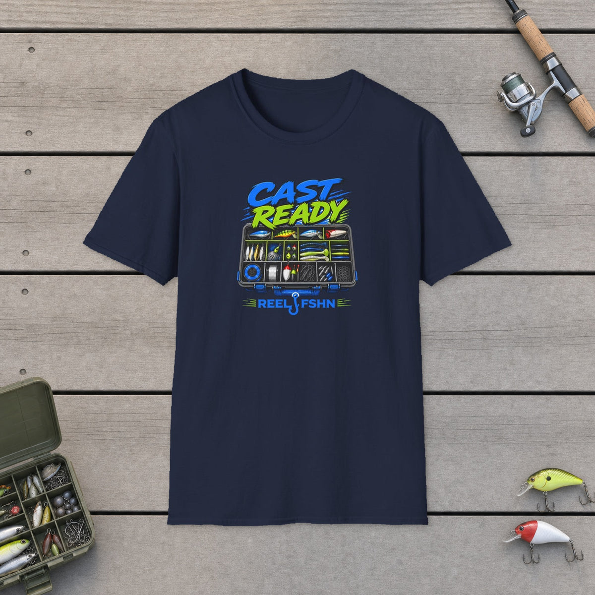 Cast Ready  T-Shirt on a wooden dock with fishing rod, reel, tackle box and lures