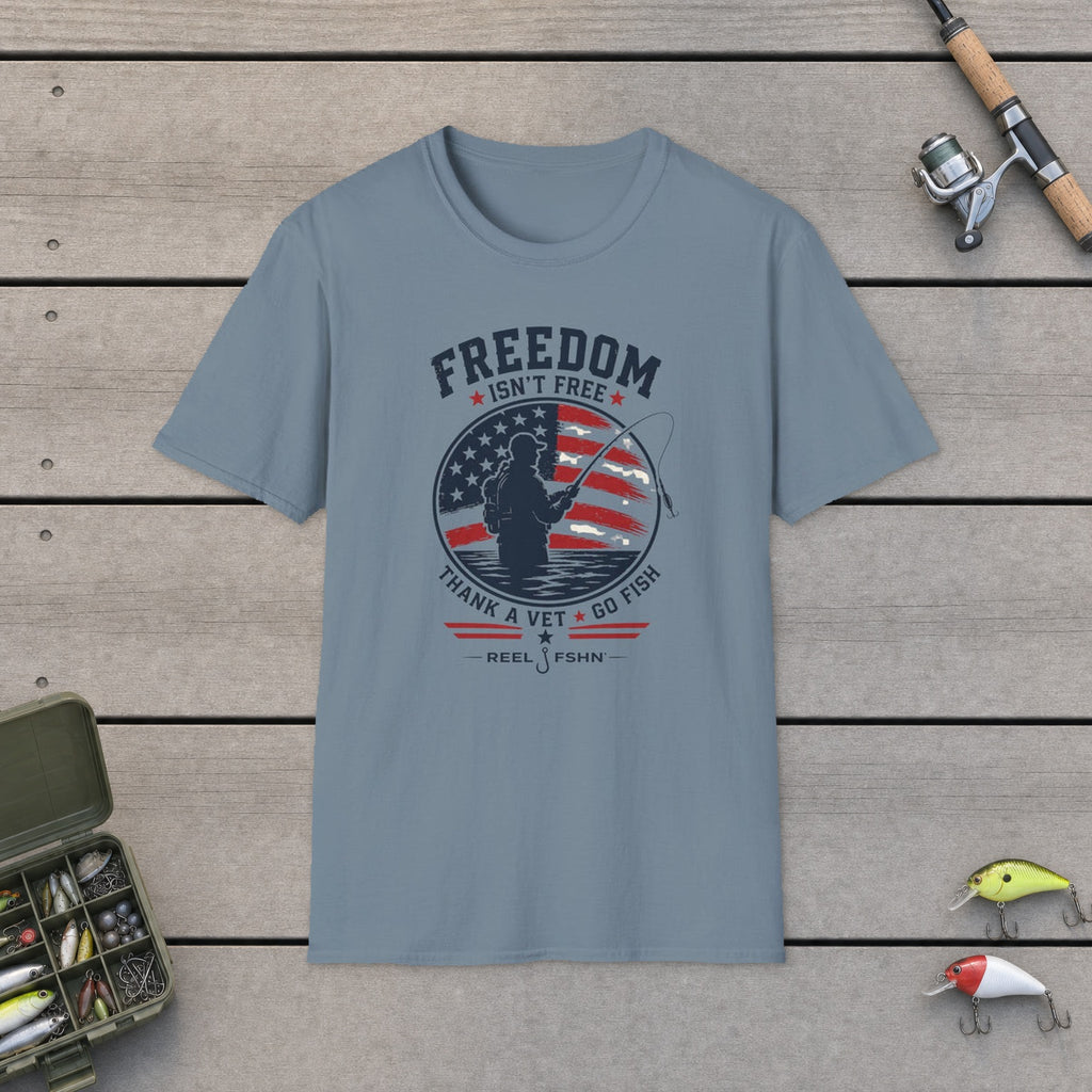 Freedom Isn't Free T-Shirt flat-laid on wooden dock boards beside a fishing rod and tackle box