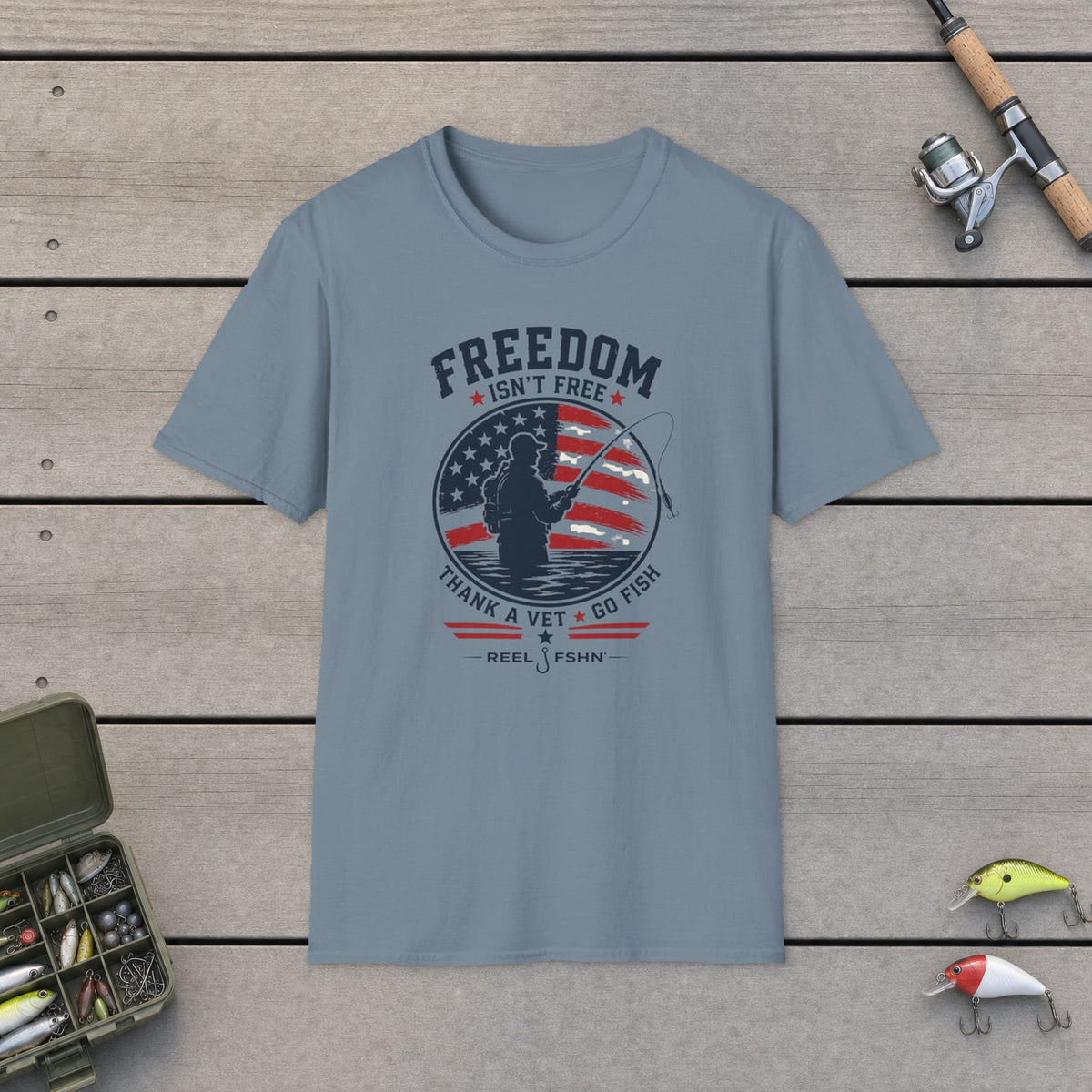 Freedom Isn't Free T-Shirt on a wooden dock with fishing rod, reel, tackle box and lures