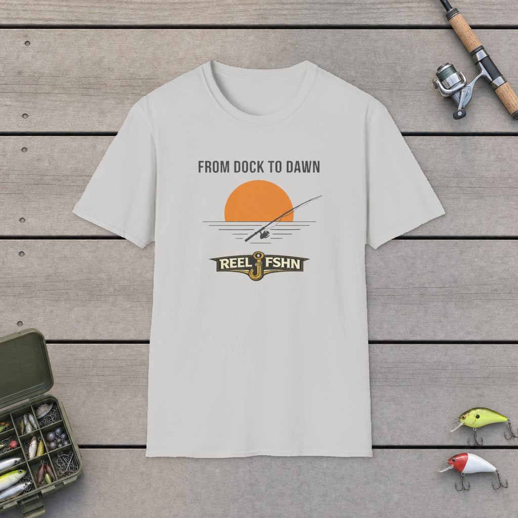 From Dock To Dawn T-Shirt flat-laid on wooden dock boards beside a fishing rod and tackle box