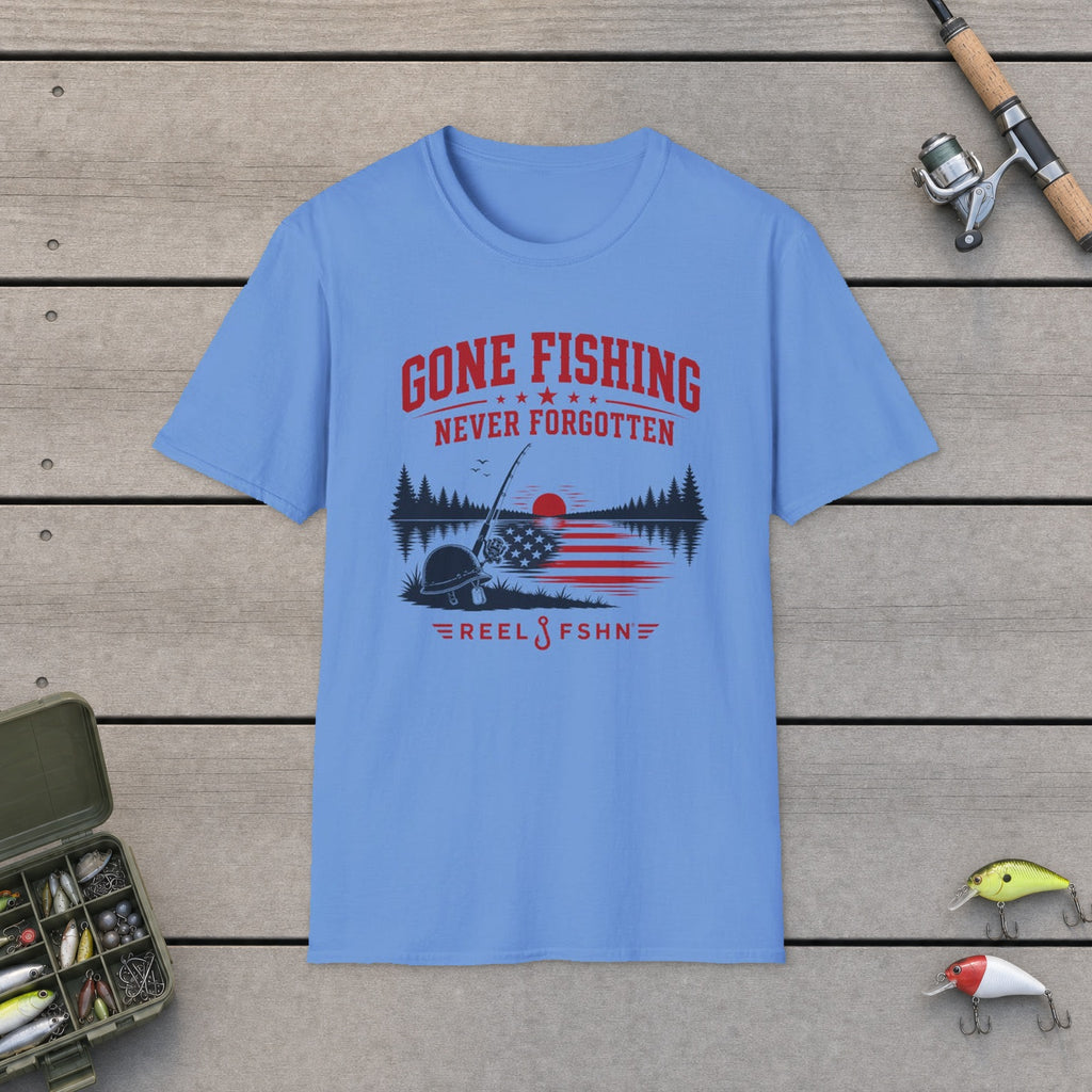 Gone Fishing Never Forgotten T-Shirt flat-laid on wooden dock boards beside a fishing rod and tackle box
