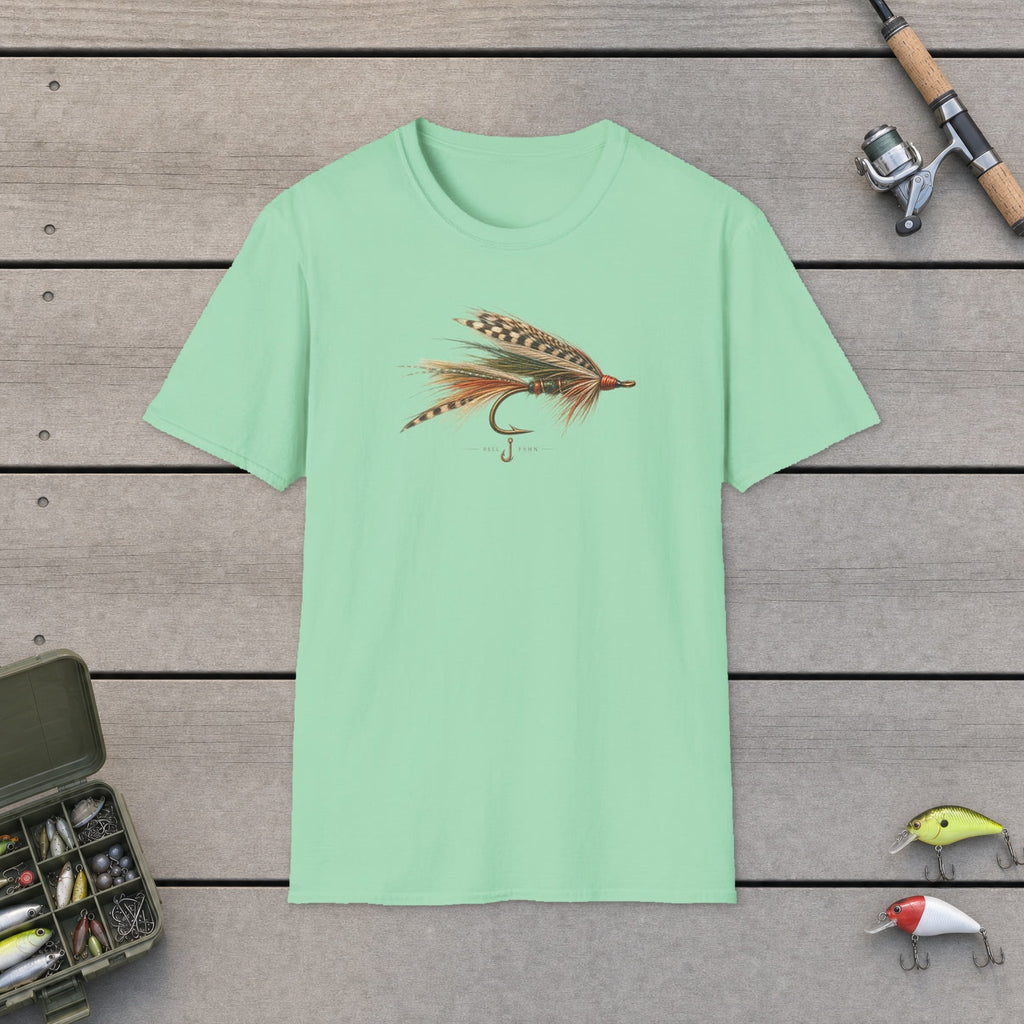 Hand Tied Fly T-Shirt flat-laid on wooden dock boards beside a fishing rod and tackle box
