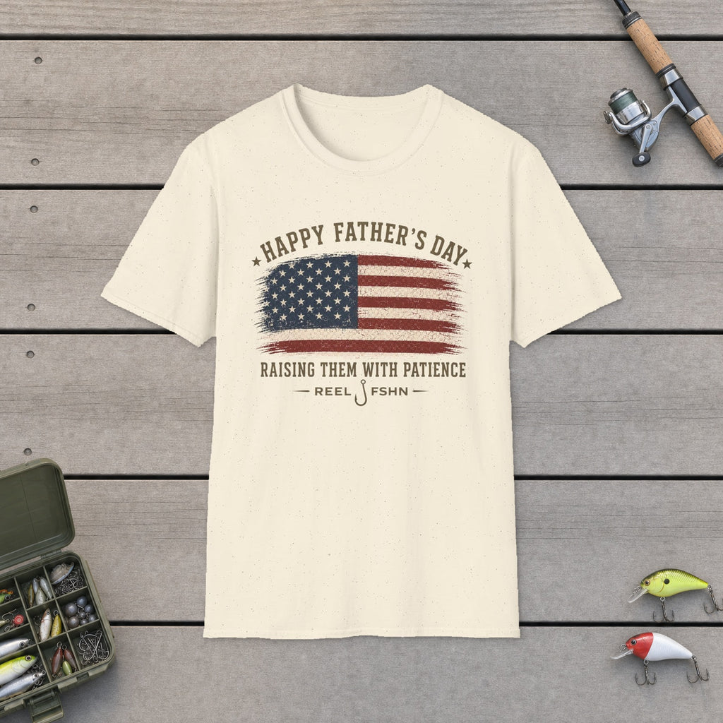 Happy Father's Day Raising Them With Patience T-Shirt flat-laid on wooden dock boards beside a fishing rod and tackle box