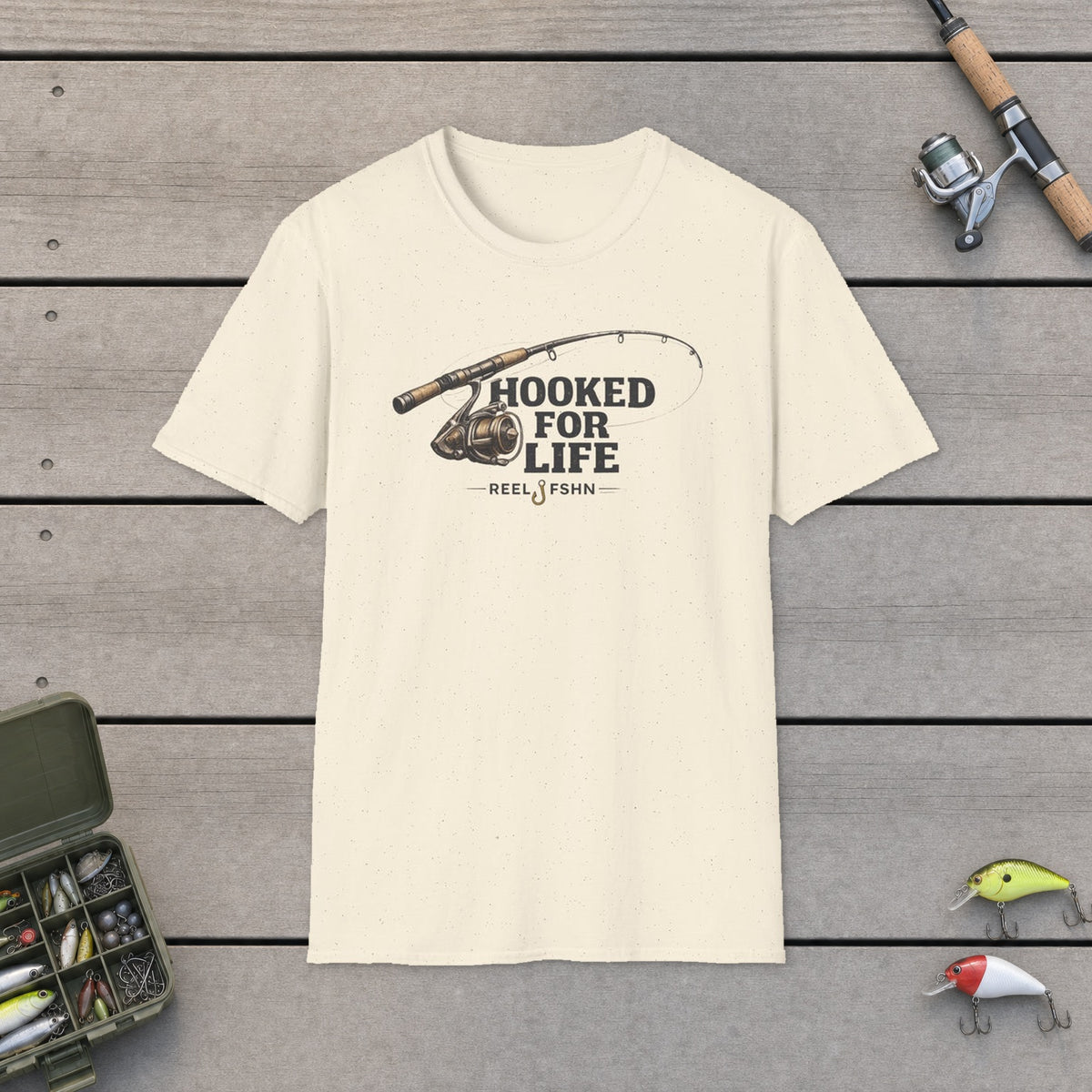 Hooked For Life T-Shirt on a wooden dock with fishing rod, reel, tackle box and lures