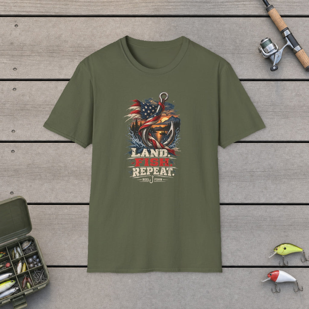 Land. Fish. Repeat. T-Shirt flat-laid on wooden dock boards beside a fishing rod and tackle box