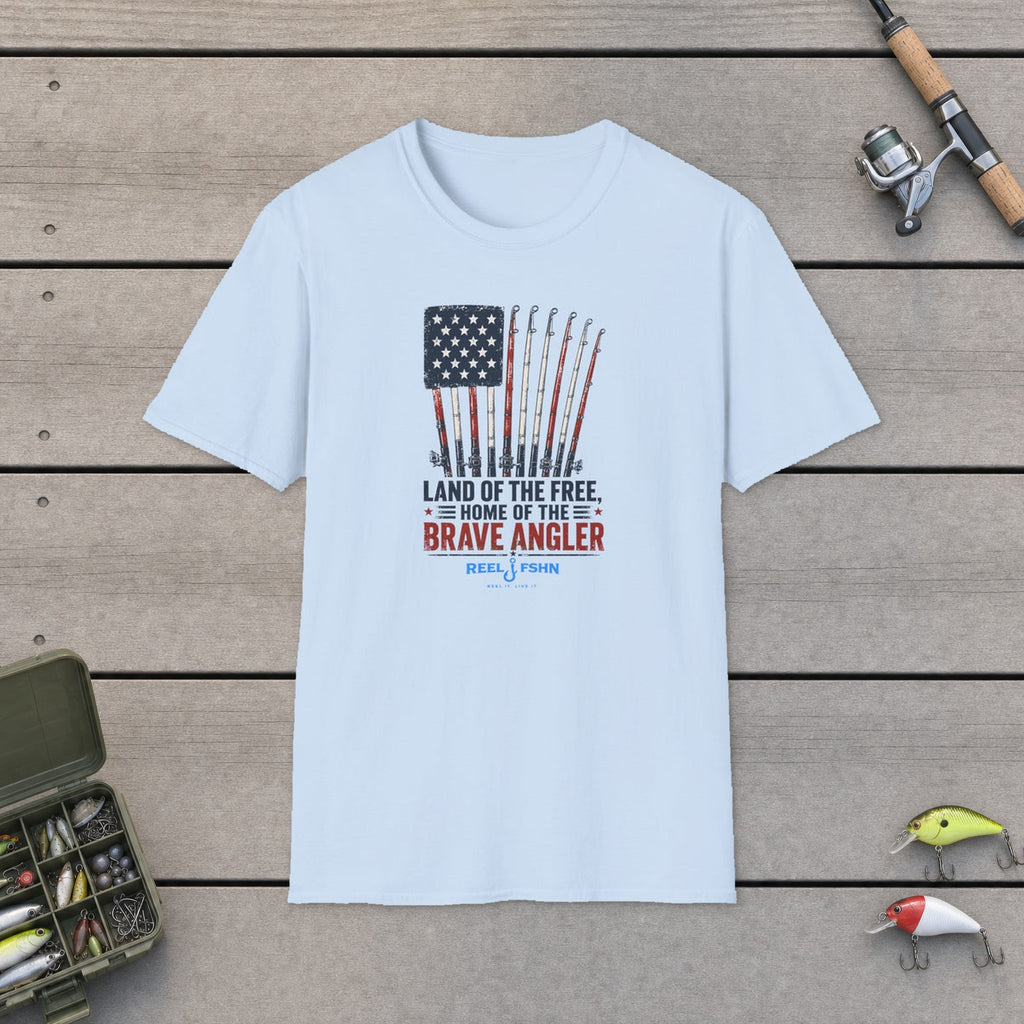 Land Of The Free Home Of The Brave Angler T-Shirt flat-laid on wooden dock boards beside a fishing rod and tackle box