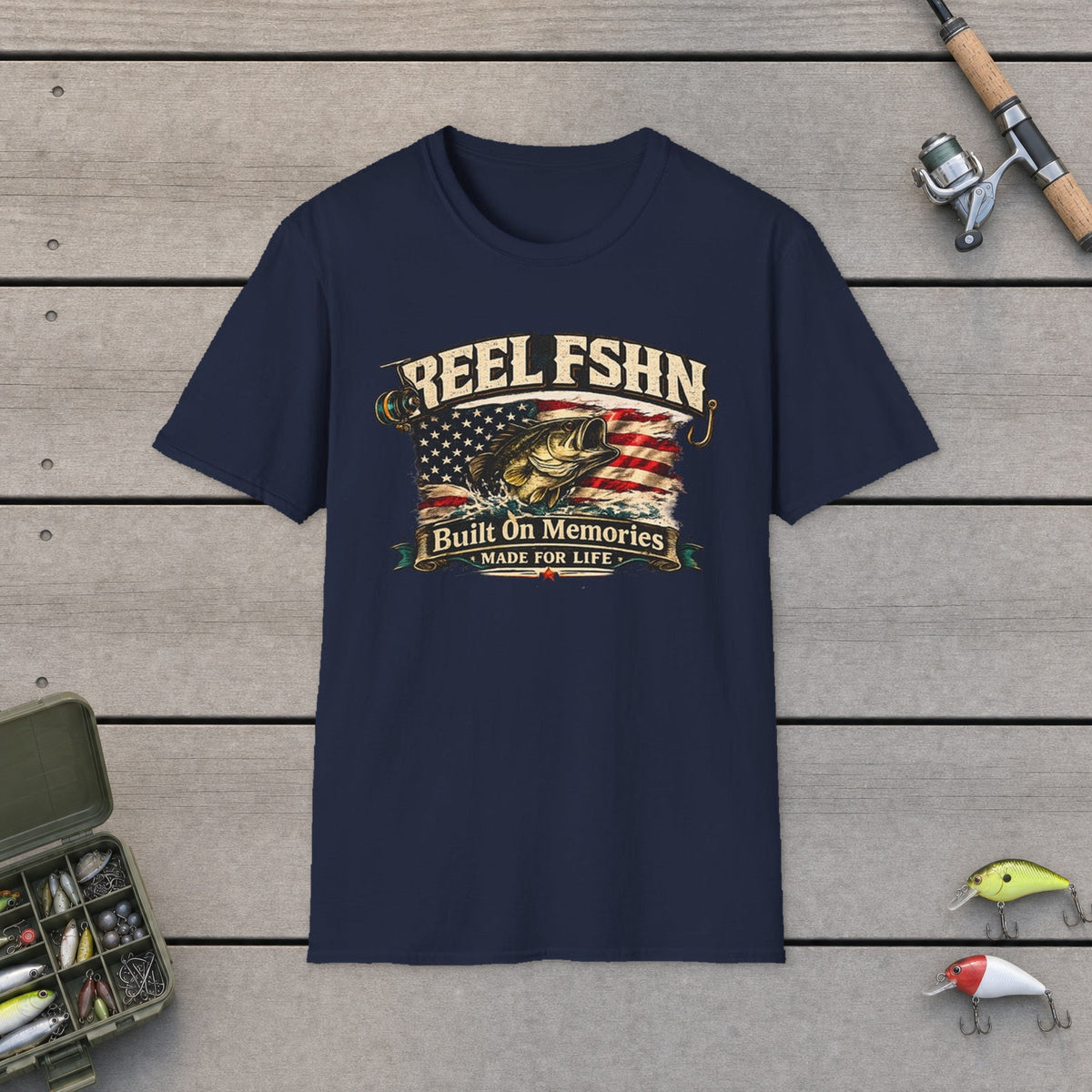 REEL FSHN Built On Memories T-Shirt on a wooden dock with fishing rod, reel, tackle box and lures