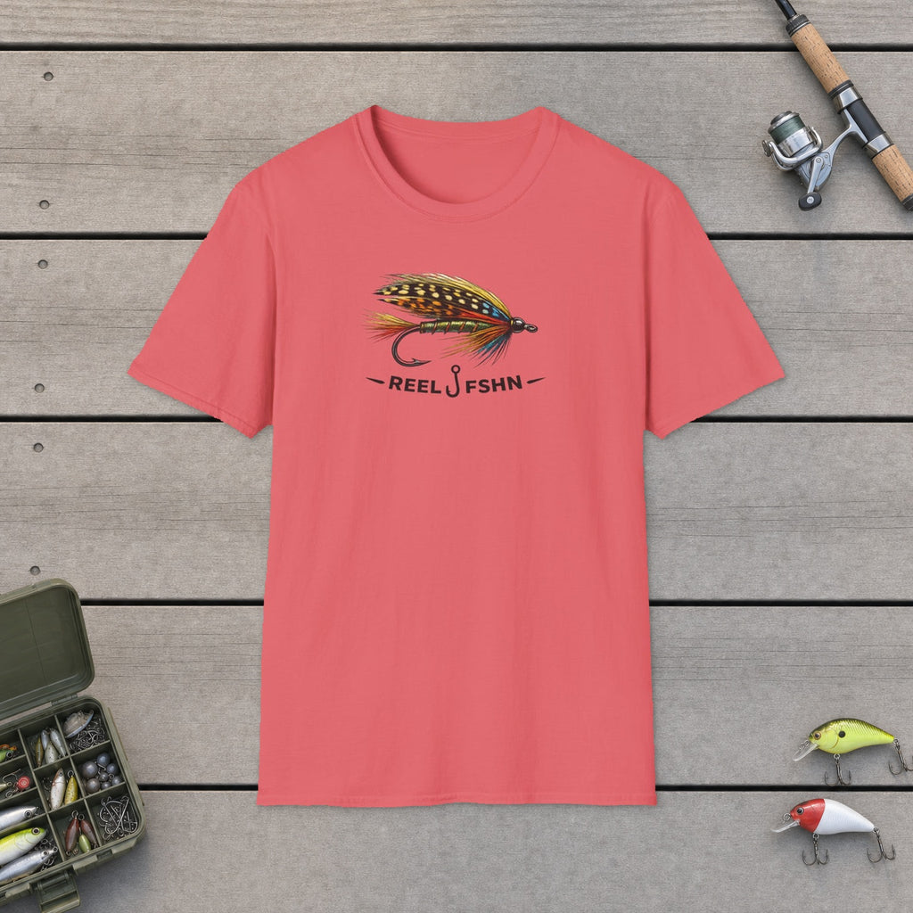 REEL FSHN FLY LURE T-Shirt flat-laid on wooden dock boards beside a fishing rod and tackle box
