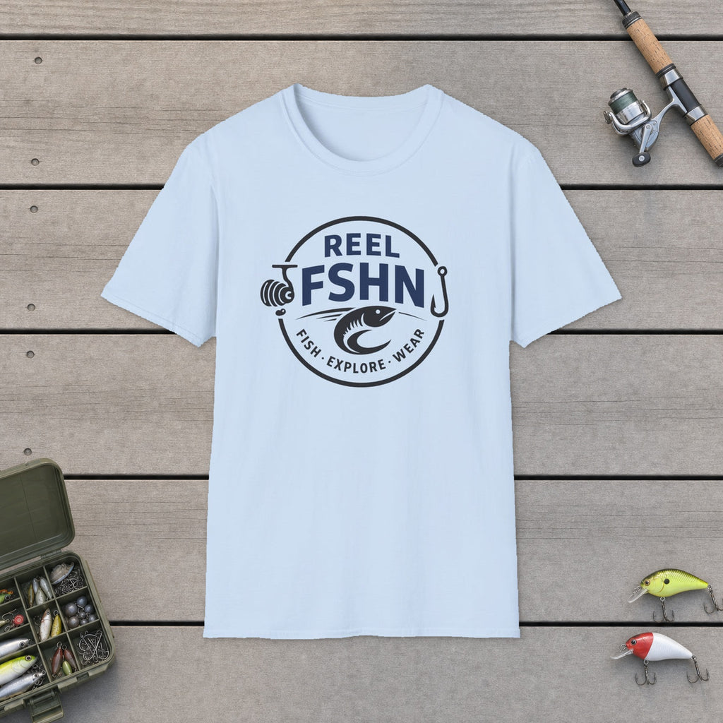 REEL FSHN LOGO T-Shirt flat-laid on wooden dock boards beside a fishing rod and tackle box