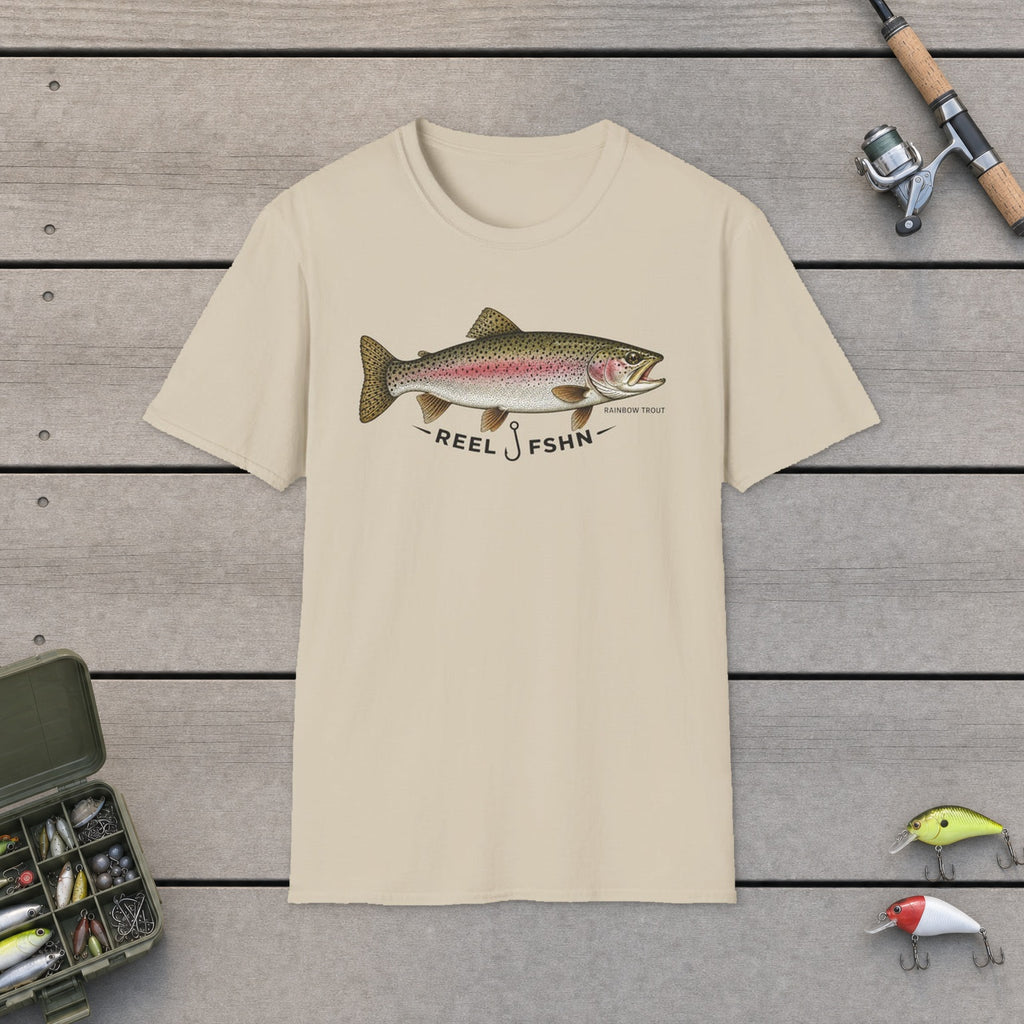 REEL FSHN RAINBOW TROUT T-Shirt flat-laid on wooden dock boards beside a fishing rod and tackle box