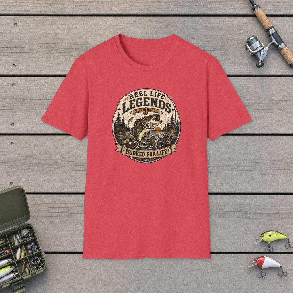 Reel Life Legends T-Shirt flat-laid on wooden dock boards beside a fishing rod and tackle box