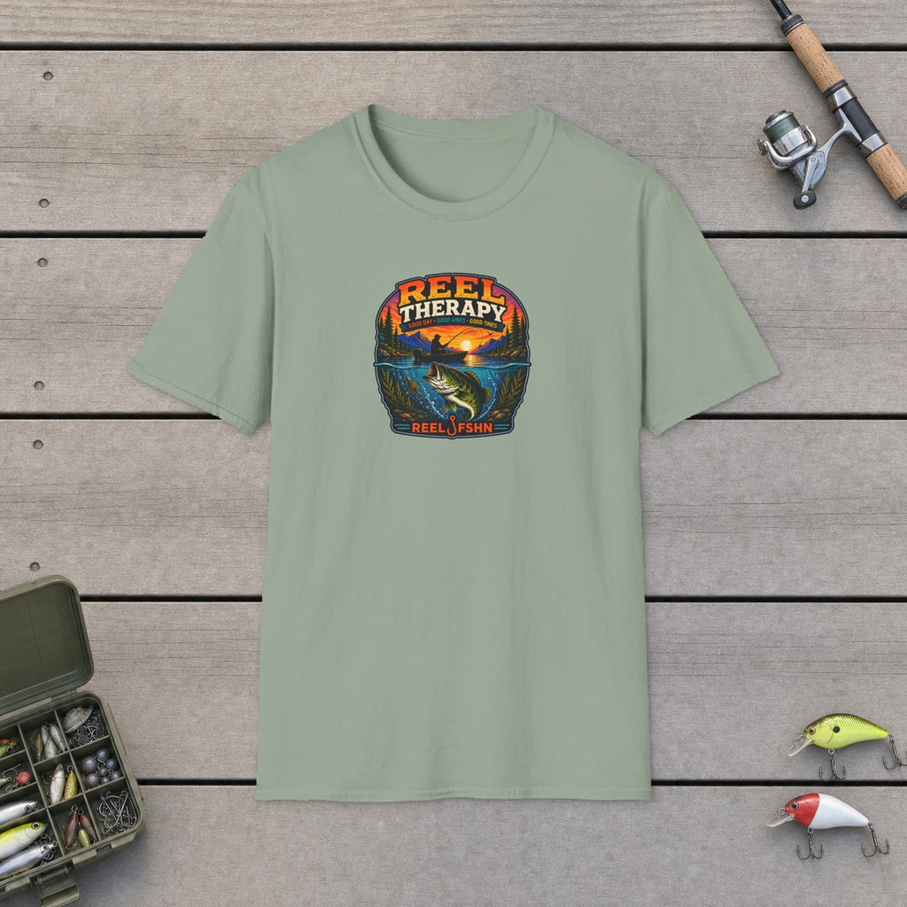 REEL Therapy T-Shirt flat-laid on wooden dock boards beside a fishing rod and tackle box