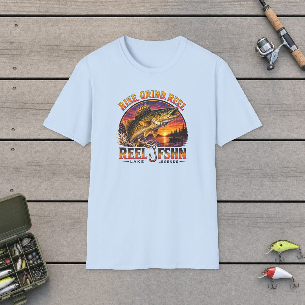 Rise, Grind, REEL T-Shirt flat-laid on wooden dock boards beside a fishing rod and tackle box