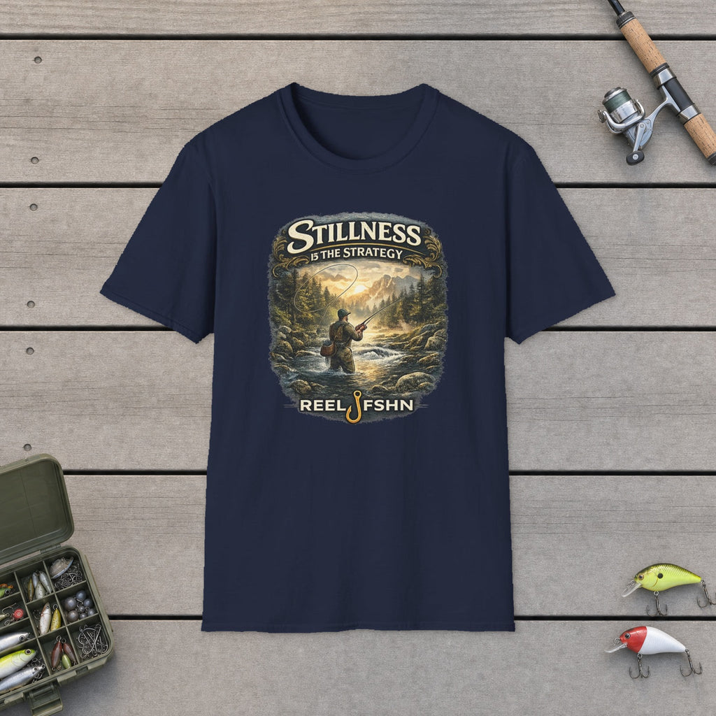Stillness Is The Strategy T-Shirt flat-laid on wooden dock boards beside a fishing rod and tackle box