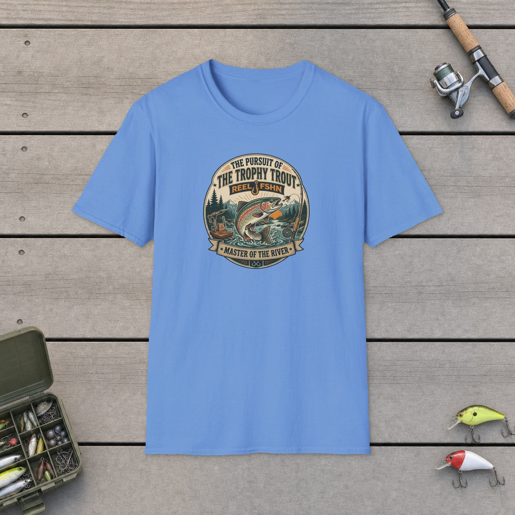 The Pursuit of The Trophy Trout T-Shirt flat-laid on wooden dock boards beside a fishing rod and tackle box