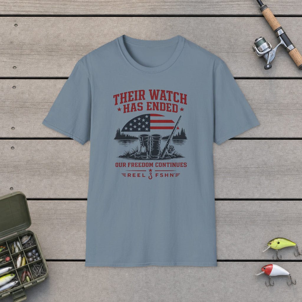 Their Watch Has Ended Our Freedom Continues T-Shirt flat-laid on wooden dock boards beside a fishing rod and tackle box