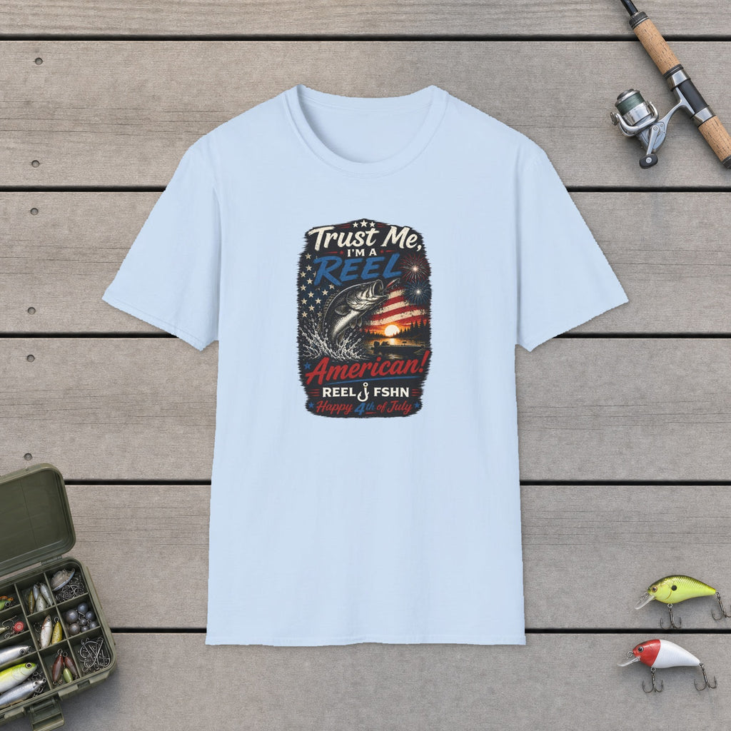 Trust Me, I'M A REEL American Happy 4th of July T-Shirt flat-laid on wooden dock boards beside a fishing rod and tackle box