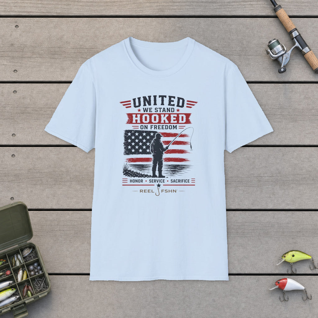United We Stand Hooked On Freedom T-Shirt flat-laid on wooden dock boards beside a fishing rod and tackle box