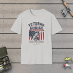 Veteran By Choice Angler Forever T-Shirt on a wooden dock with fishing rod, reel, tackle box and lures